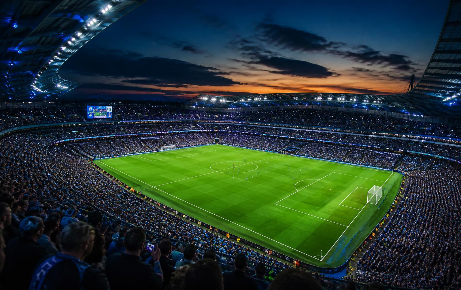 Floodlit soccer stadium at dusk on a match night